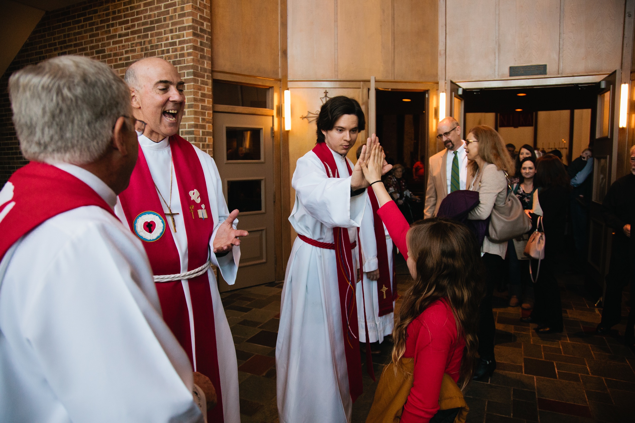 A pastor high-fives a child at the church entrance.